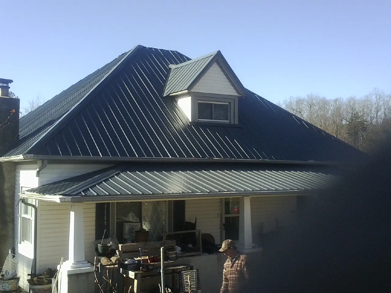 Dark blue standing seam metal roof with a dormer above a front porch in Steamboat Springs