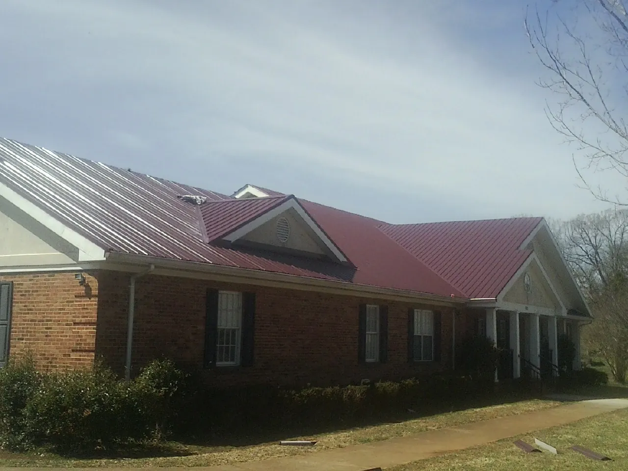 Red metal roof with gabled entries on a long brick building, from a Hail Damage Roof Repair job in Steamboat Springs