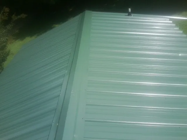 New green metal panels meeting at the ridge of a roof — Flat Roof Repair work by our crew in Steamboat Springs