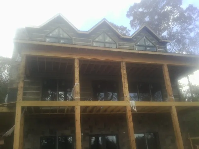 Dormers and porch framing on a large log home under construction — Roof Coating work by our crew in Steamboat Springs