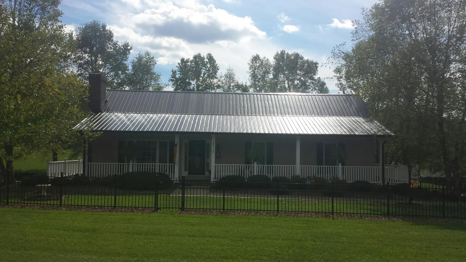 Gray metal roof on a brick ranch with a full width front porch — Gutter Guard Installation work by our crew in Steamboat Springs