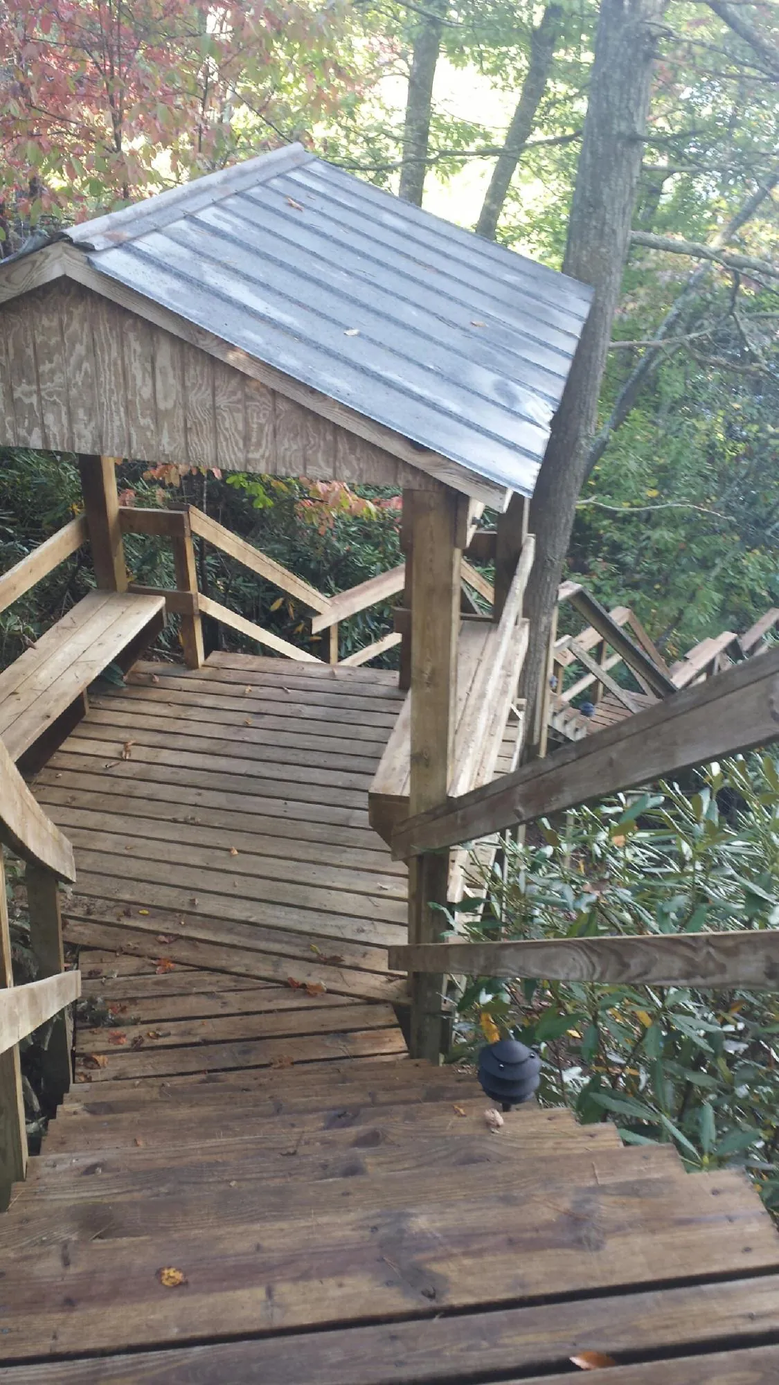 Metal roofed shelter over wooden steps on a wooded walkway — Skylight Repair & Installation work by our crew in Steamboat Springs