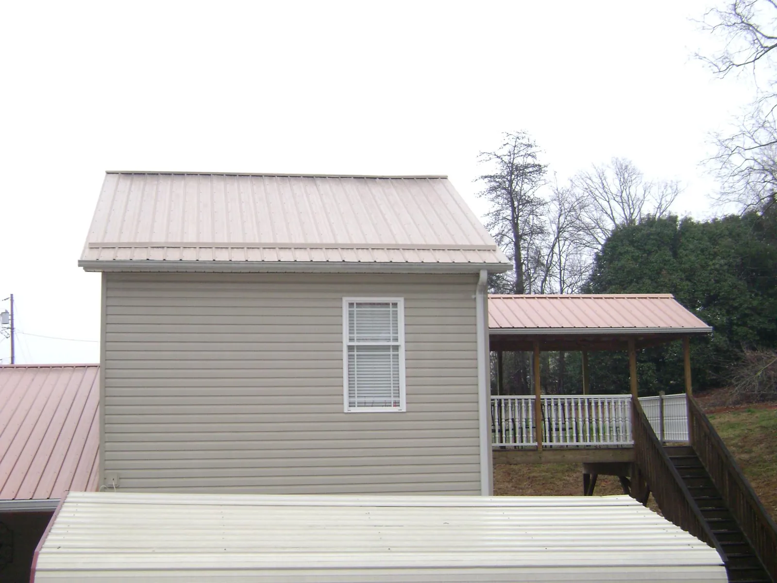 Tan metal roofs on a two story addition and attached porch, from a Roof Replacement job in Steamboat Springs