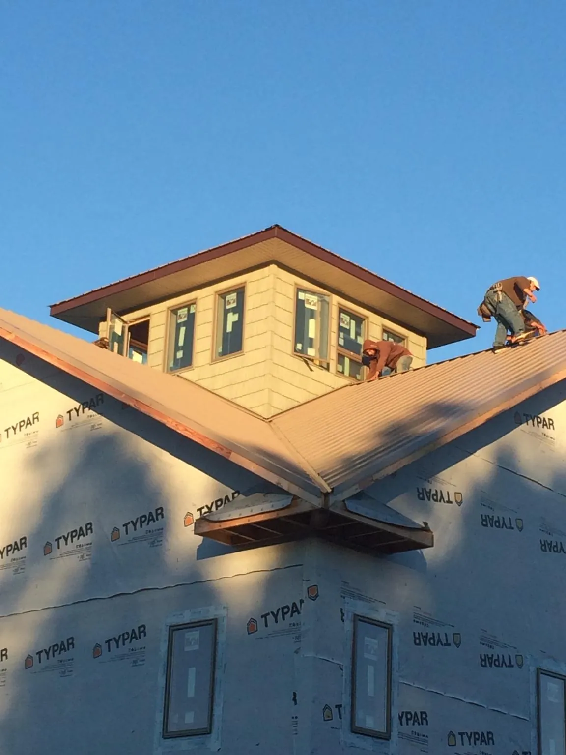Roofers working around a rooftop cupola on a new metal roof at sunset — Roof Waterproofing in Steamboat Springs by Roofing Brothers